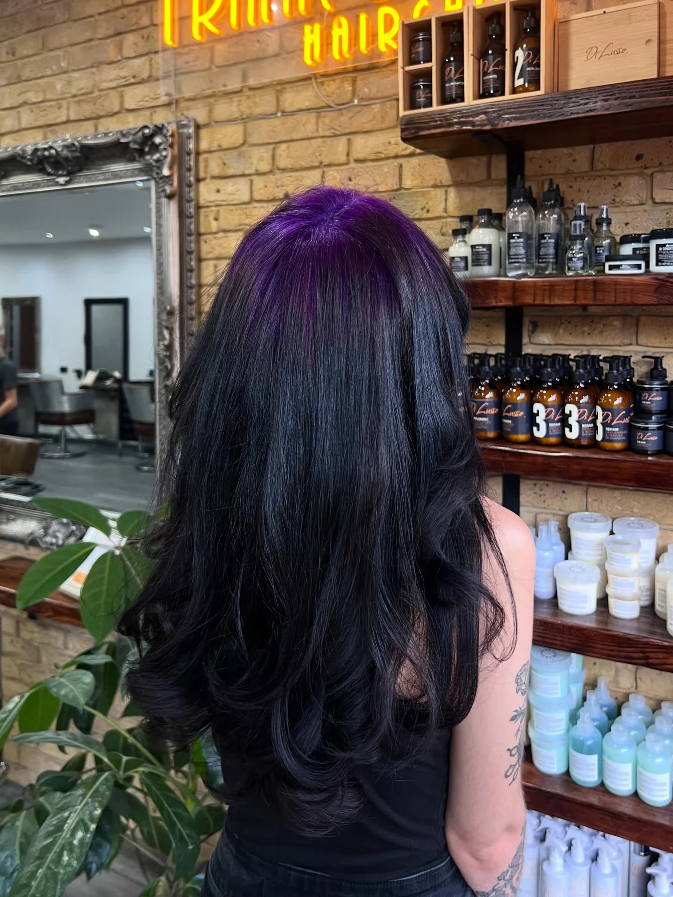 Back view of long glossy black layered hair with a deep-violet crown panel.
