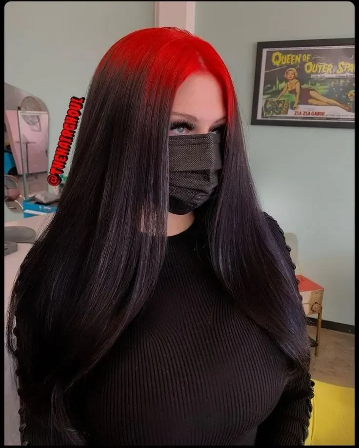 Woman with long sleek dark brown hair and cherry-red color along the center-part root zone.