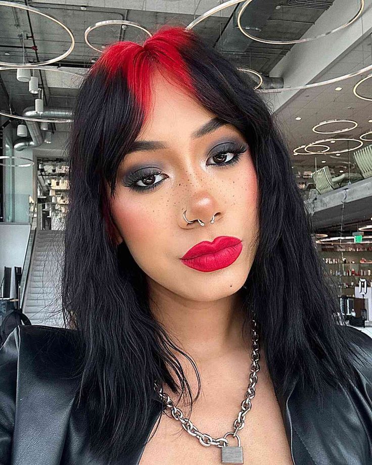 Straight black hair with deep red ghost roots and airy curtain bangs.