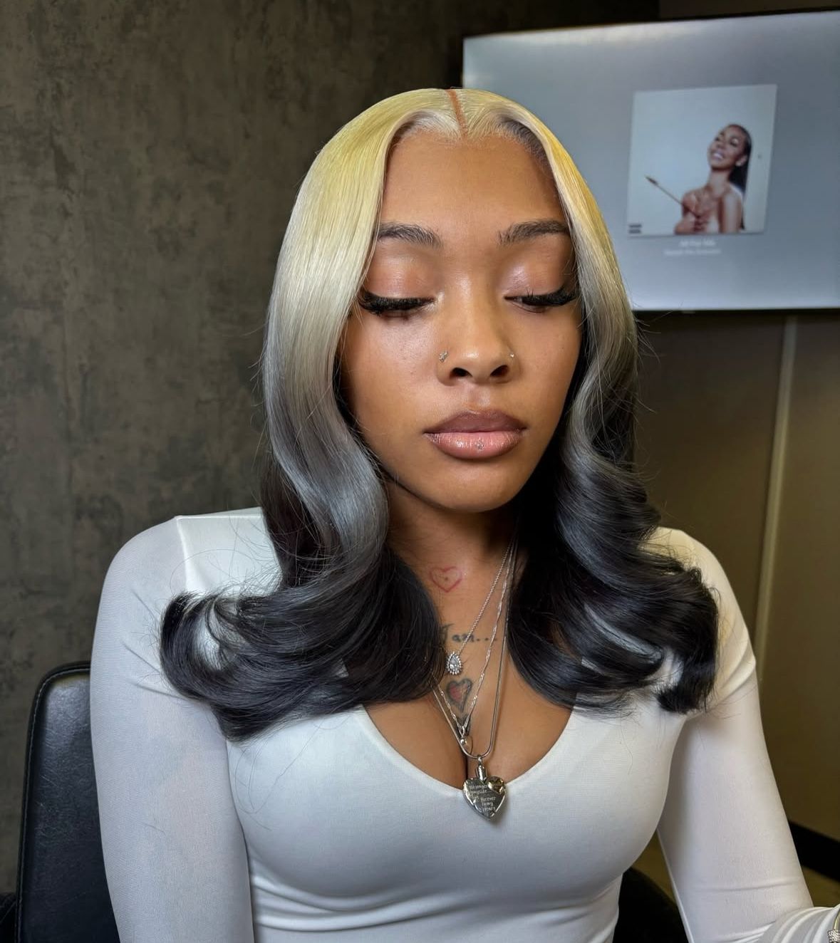 Shoulder-length curled style with buttery blonde roots and smoky charcoal ends.