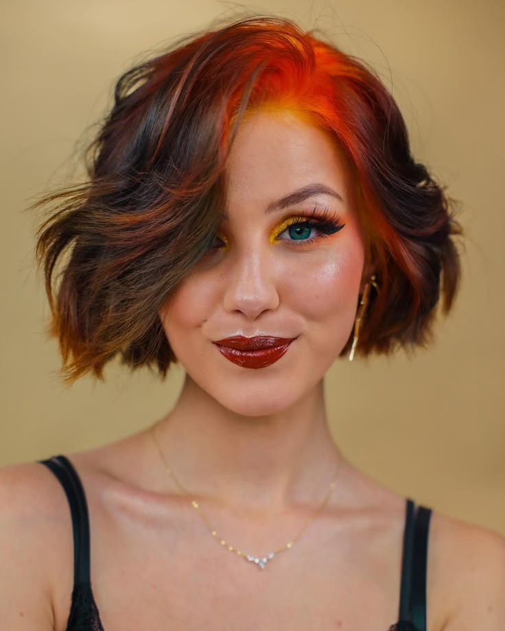 Short wavy brunette bob with vivid copper-orange ghost roots and a deep side part.