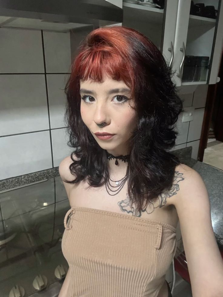 Shaggy dark brown wolf cut with muted copper-red ghost roots and short fringe.