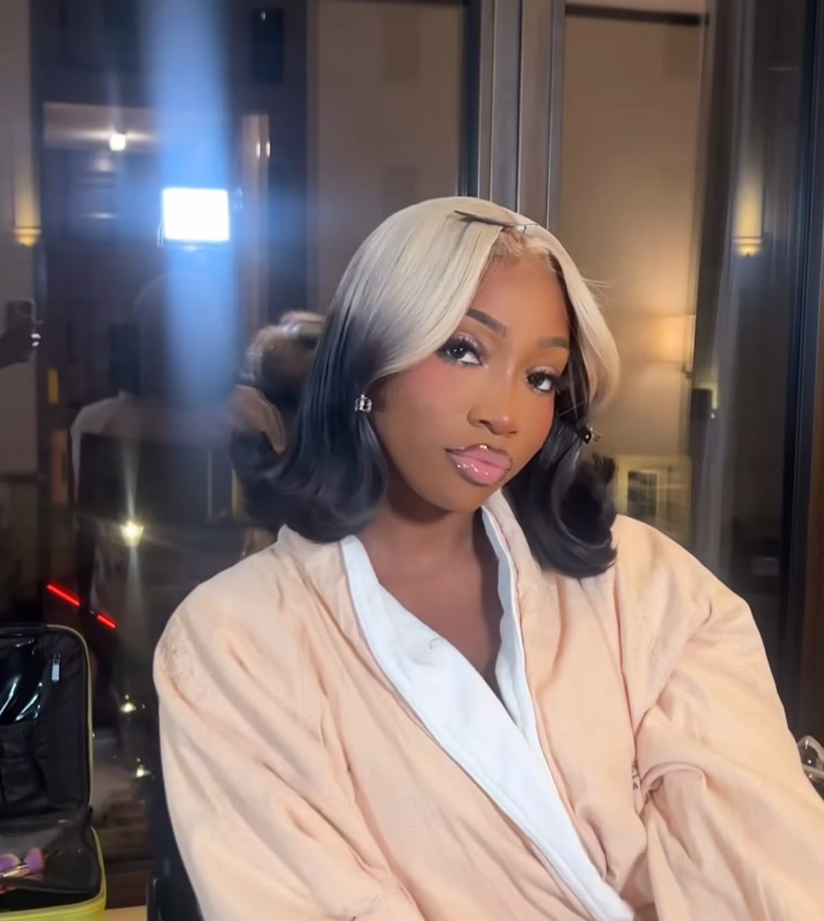 Short black curled bob with platinum ghost roots and face-framing bends.