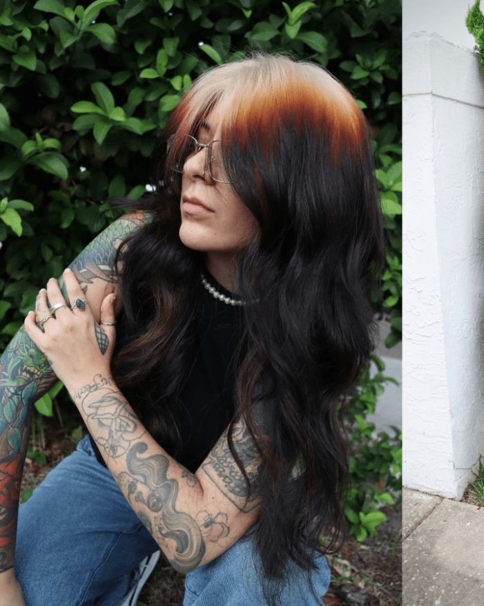 Long black waves with warm copper-blonde ghost roots and face-framing layers.