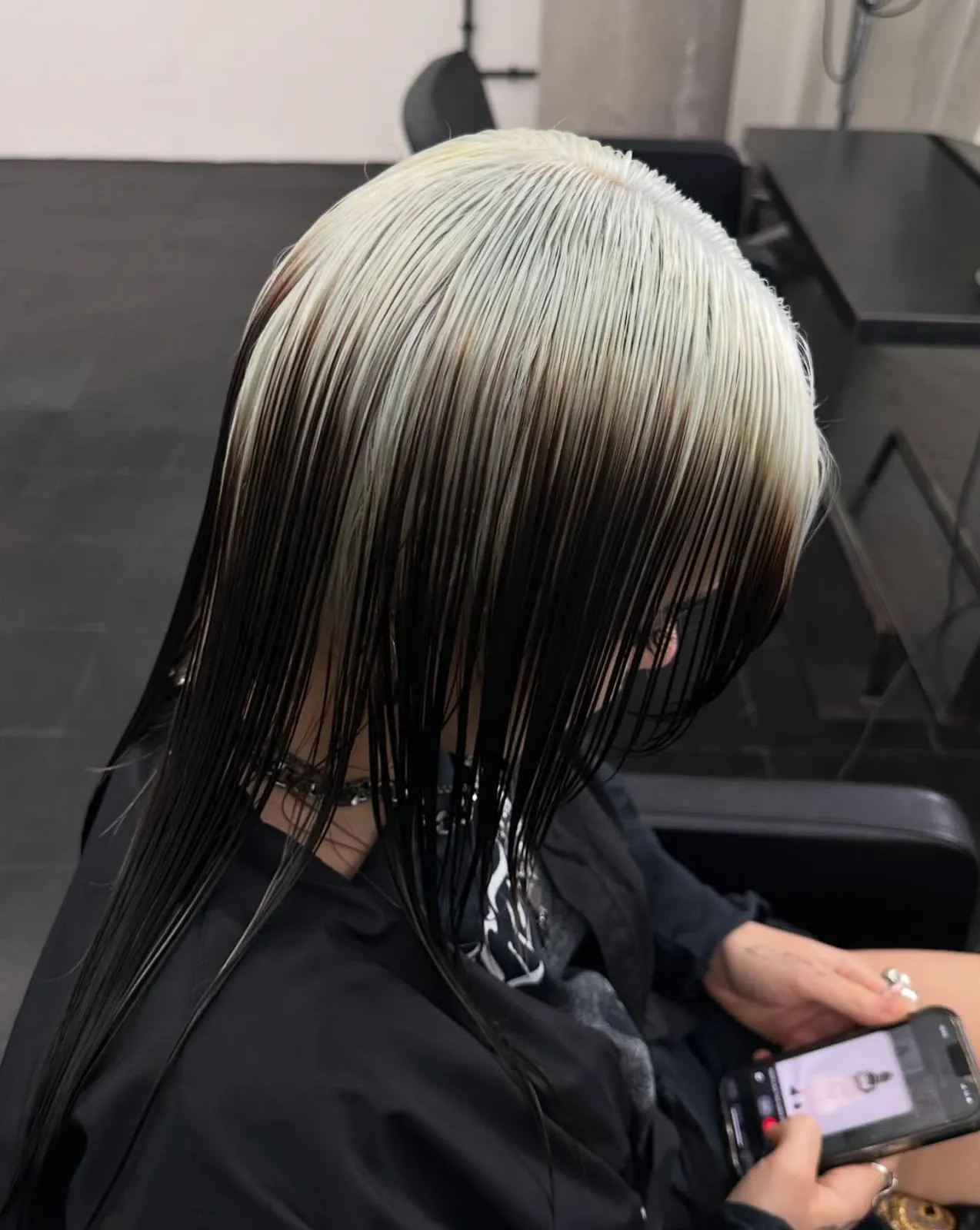 Sleek shoulder-length cut with platinum blonde roots melting into inky black lengths.