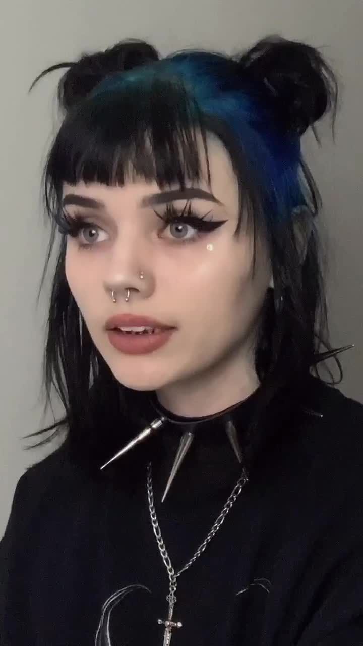 Black double-bun style with cobalt blue ghost roots and blunt bangs.