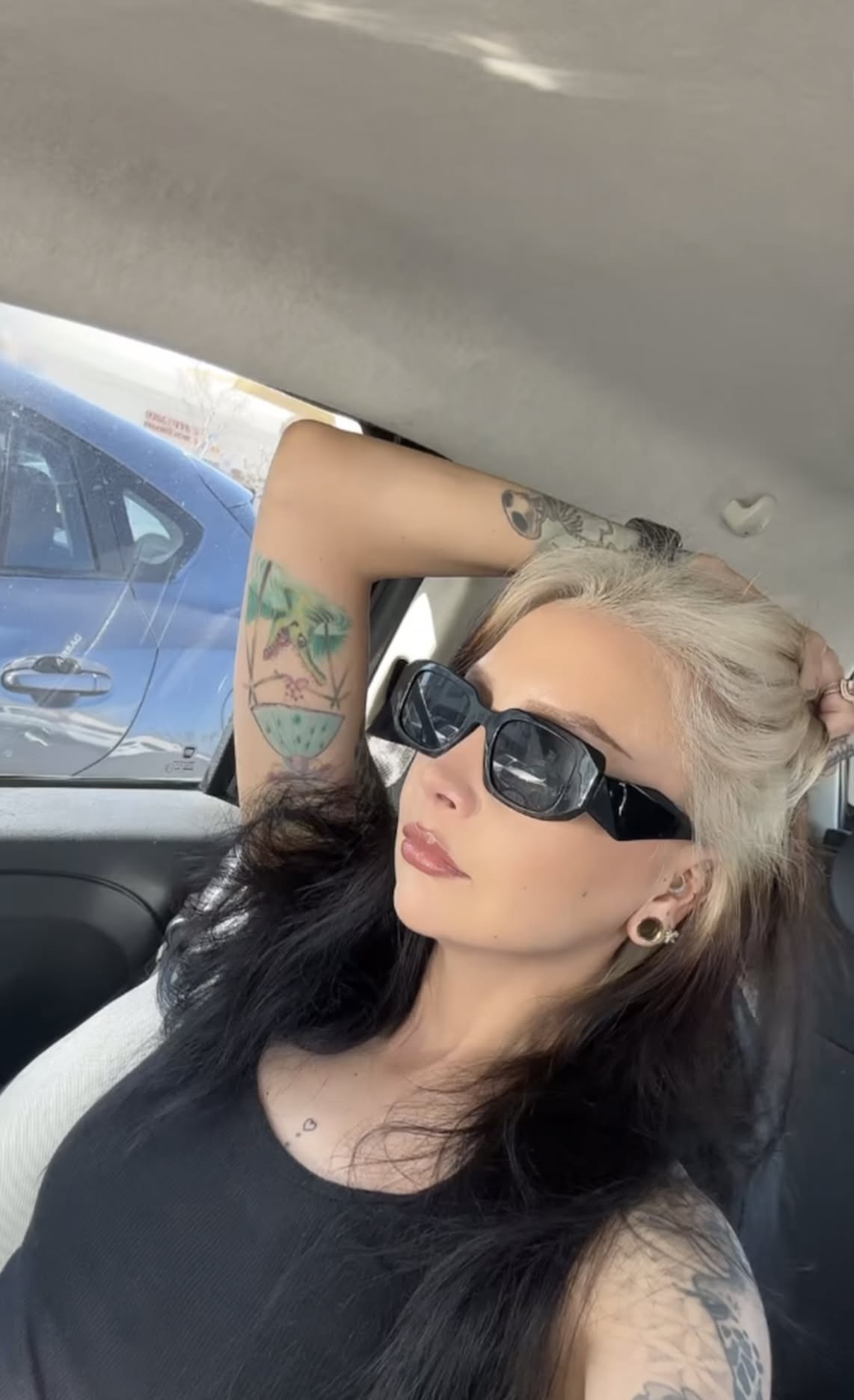 Long black hair with icy platinum ghost roots pulled into a half-up style.