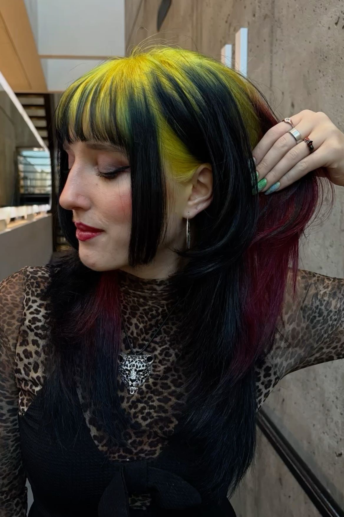 Layered black cut with neon yellow ghost roots, blunt bangs, and hidden red panels underneath.