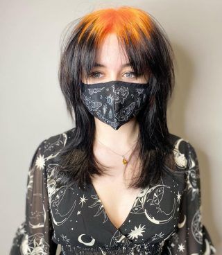Black shag haircut with bright orange ghost roots and wispy fringe.