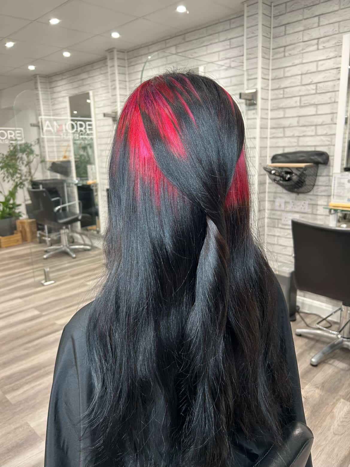 Long black hair with vivid magenta ghost-root streaks through the crown and side sections.