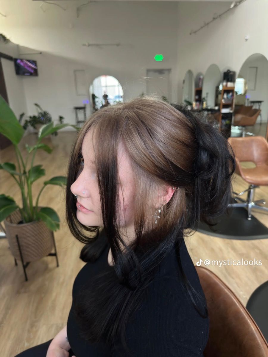 Half-up black hairstyle with mushroom blonde ghost roots and face-framing tendrils.