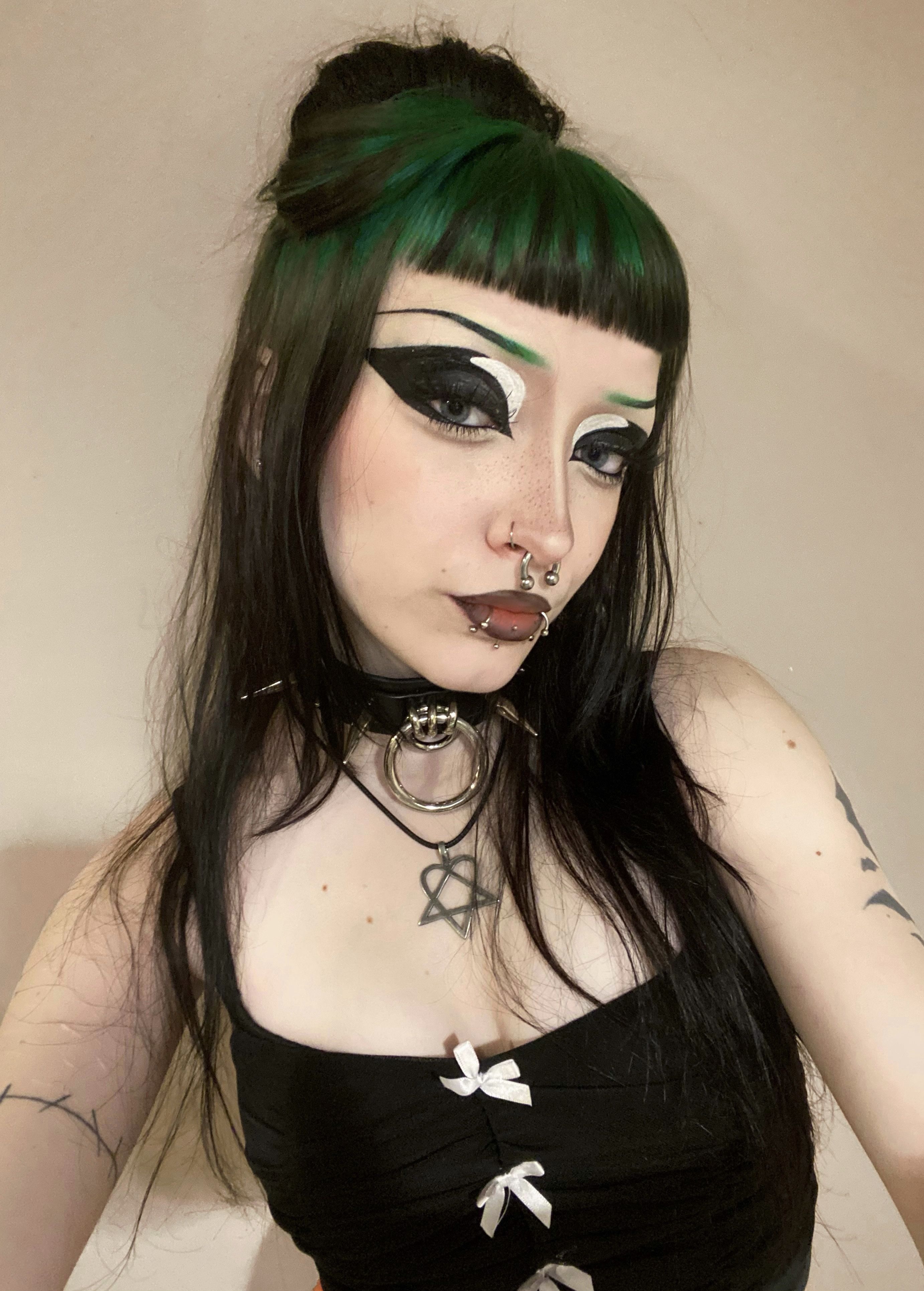 Long black hair with forest-green ghost roots and blunt micro bangs.