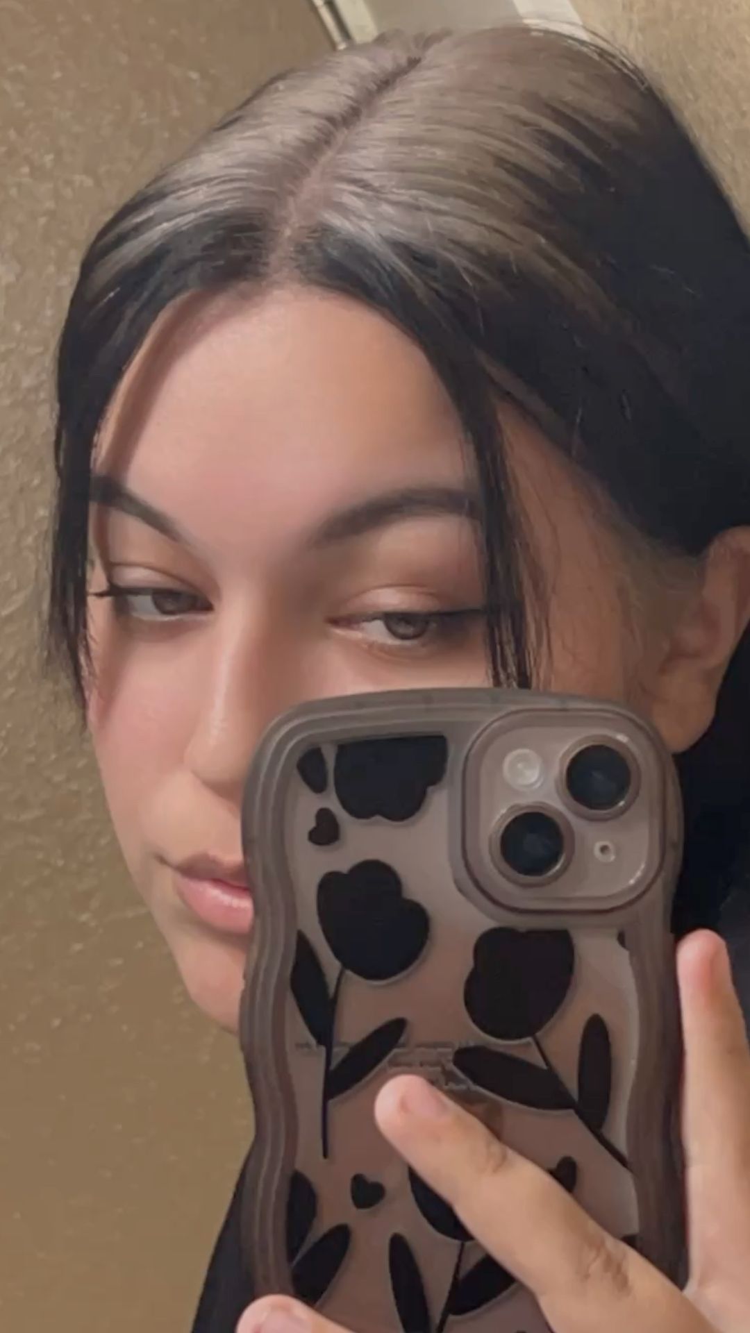 Sleek black hair with mushroom-brown ghost roots and a center-part face frame.