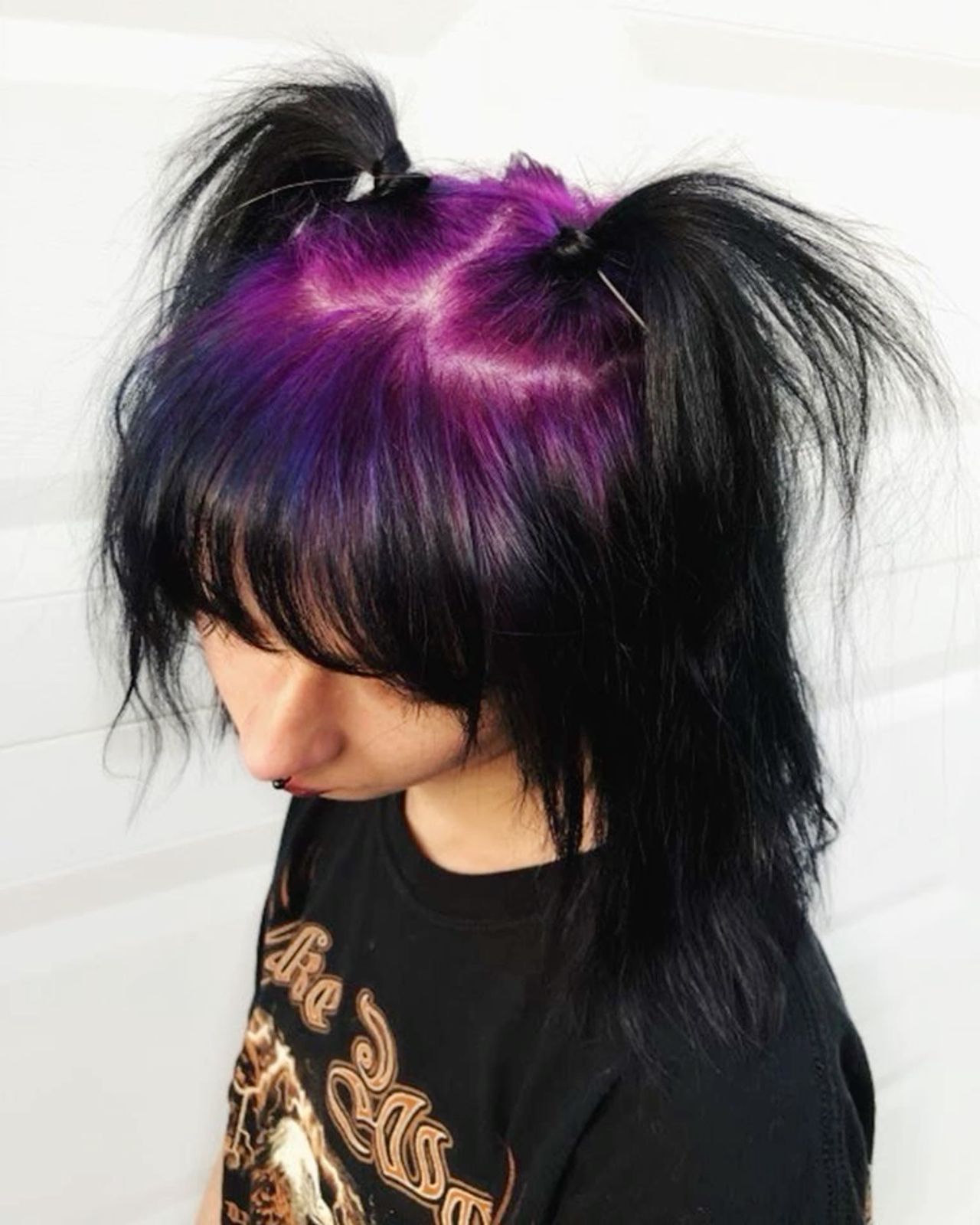 Black pigtail style with violet-purple ghost roots and blunt bangs.