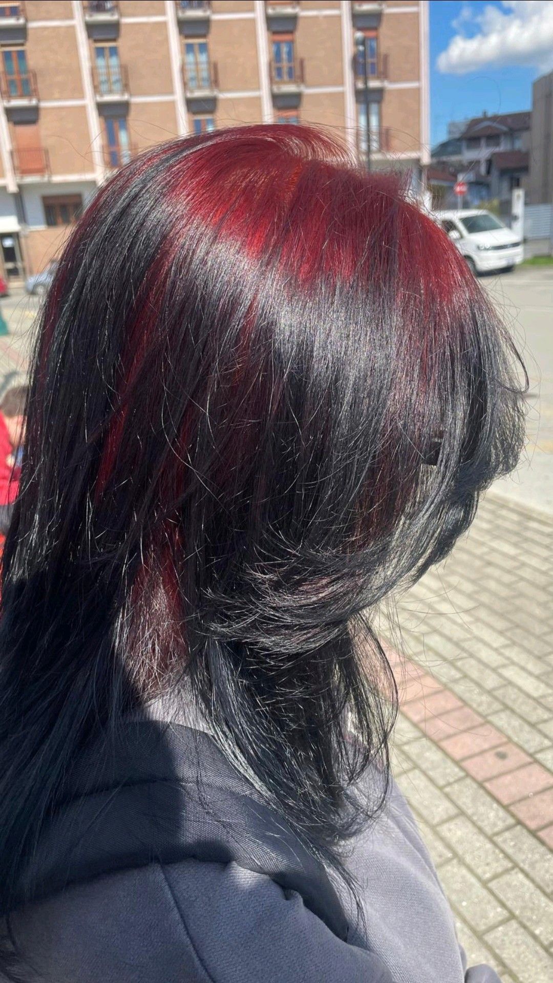 Black layered cut with deep crimson ghost roots sweeping across the crown.