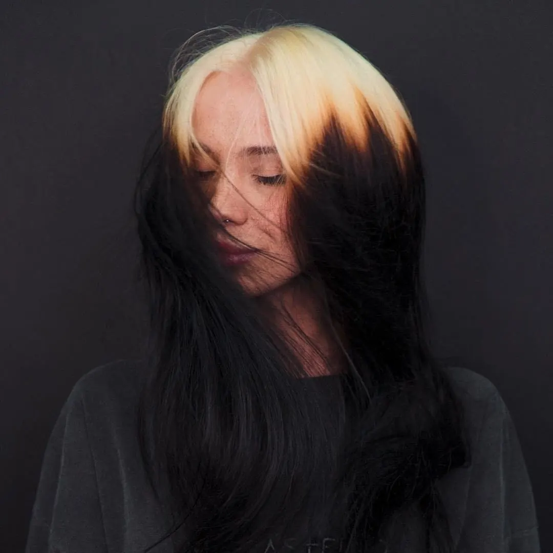 Long sleek black hair with bold blonde ghost roots near the front and crown.