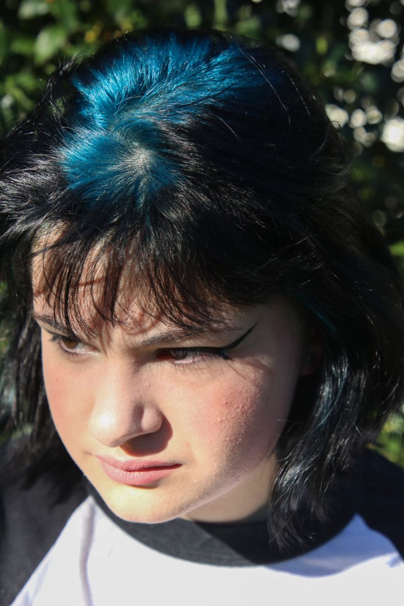 Short black layered shag with bright blue-teal ghost roots through the crown.