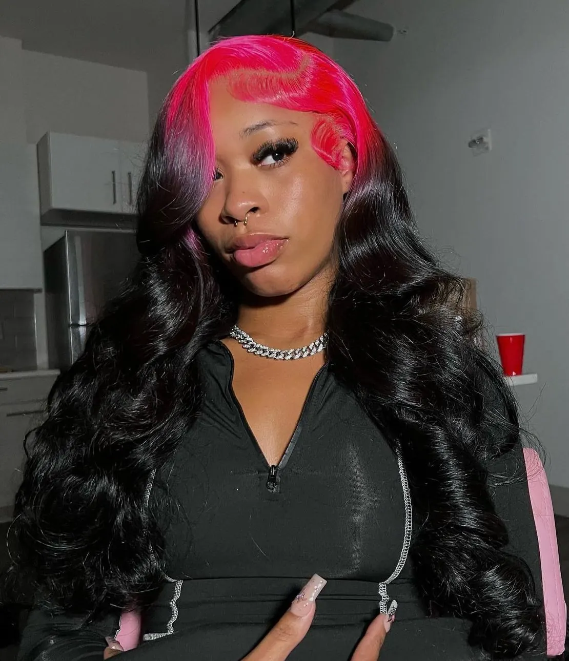 Long black glam waves with hot pink ghost roots and a center part.