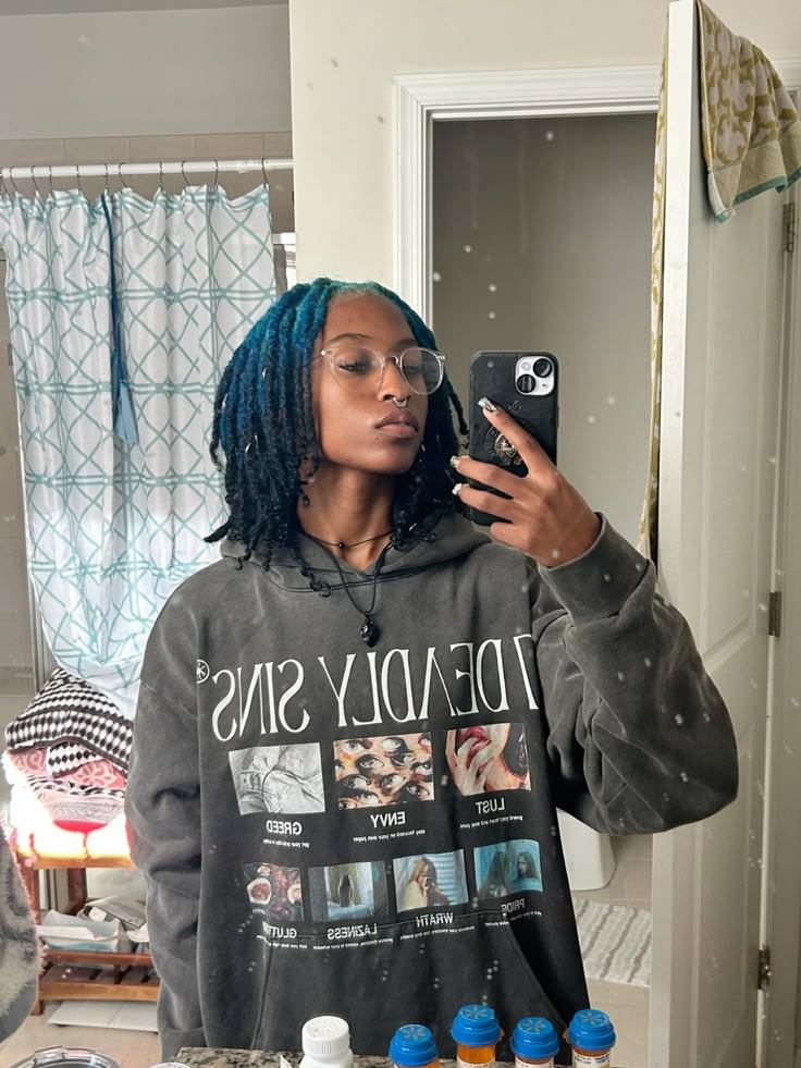 Medium black locs with teal-blue ghost roots through the crown and front rows.